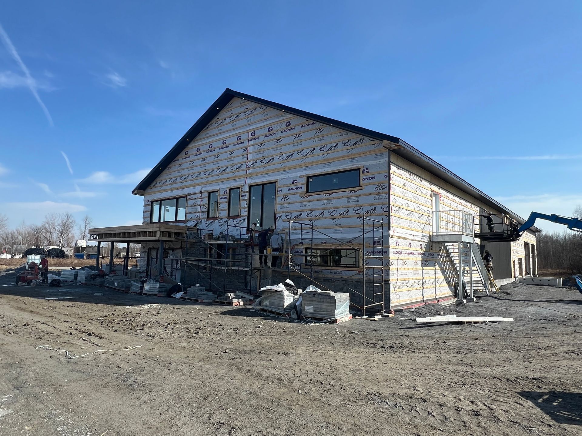 Un grand bâtiment en briques est en cours de construction dans un champ de terre.