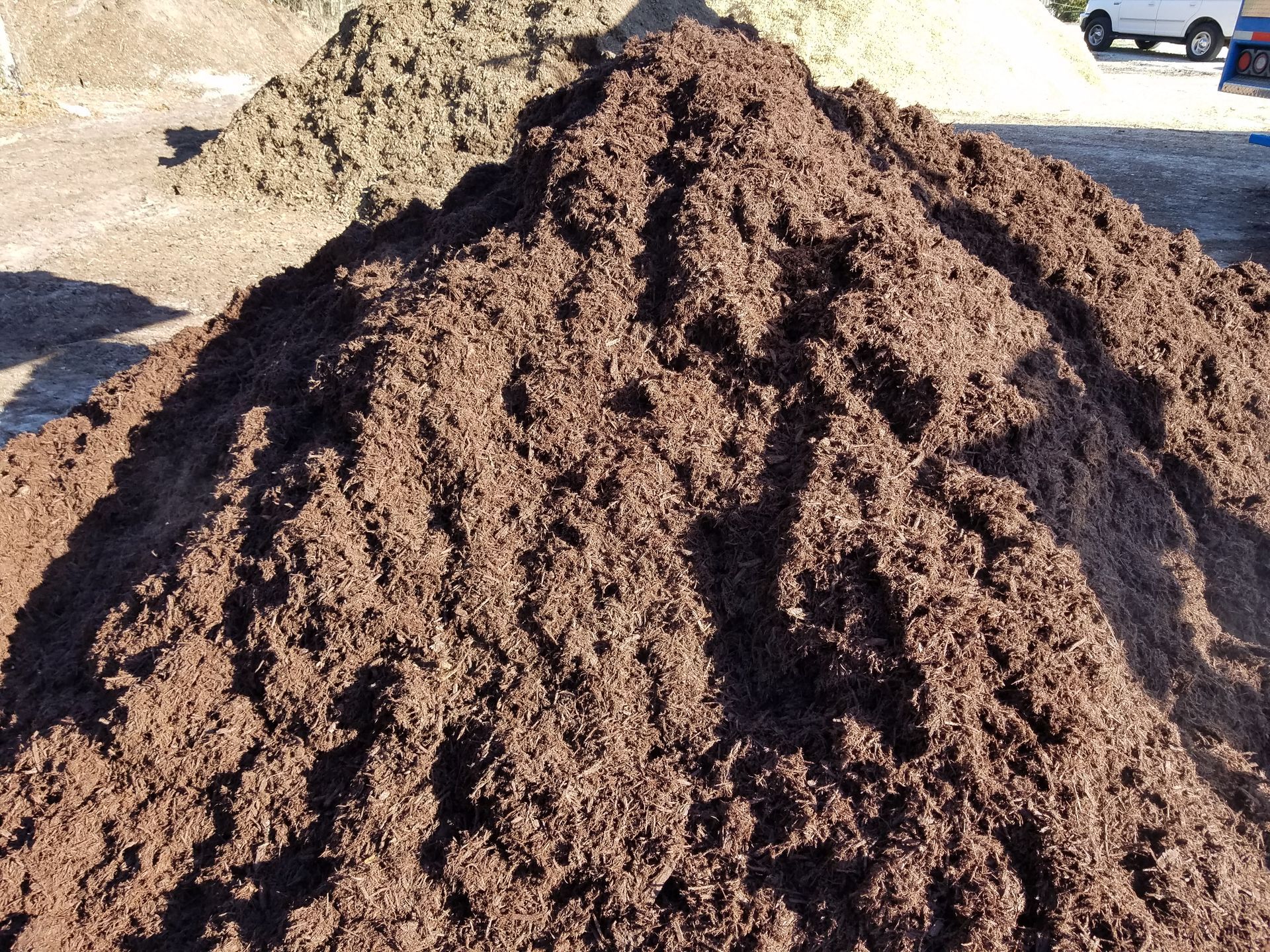 Pile of dark brown mulch, likely for gardening.