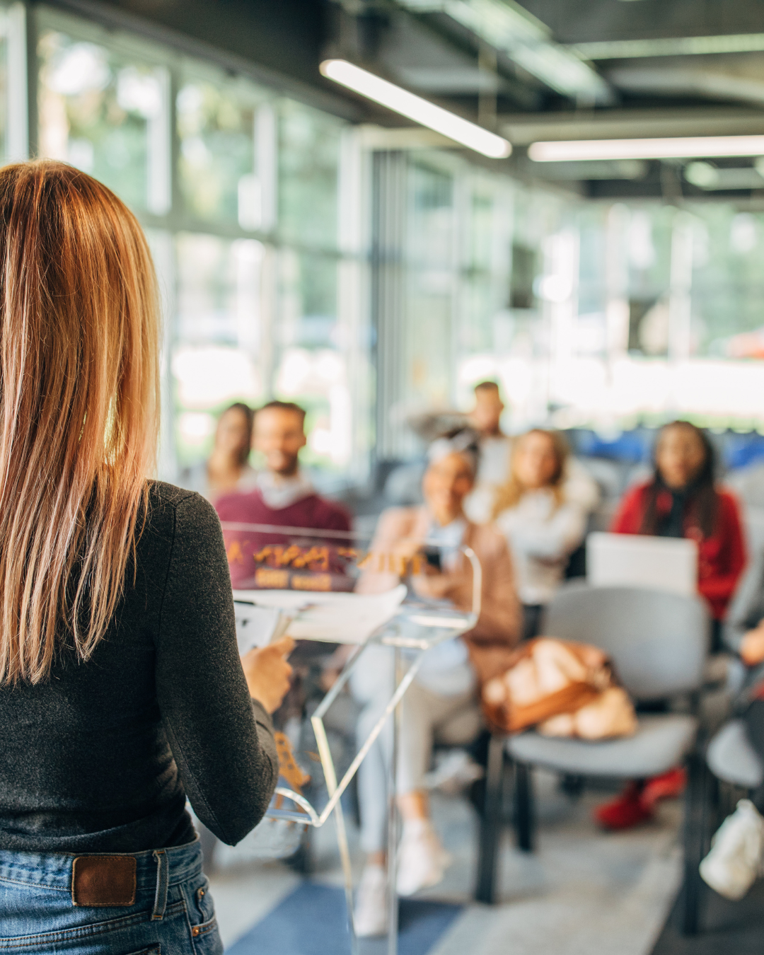 A woman is standing at a podium giving a presentation to a group of people.