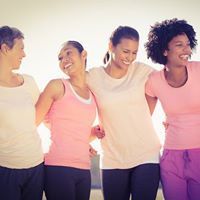 Group of women of all ages with arms around each other, smiling and laughing