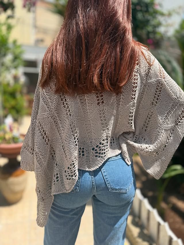 Persona in piedi all'aperto con una maglietta bianca larga e jeans blu, vista di spalle.
