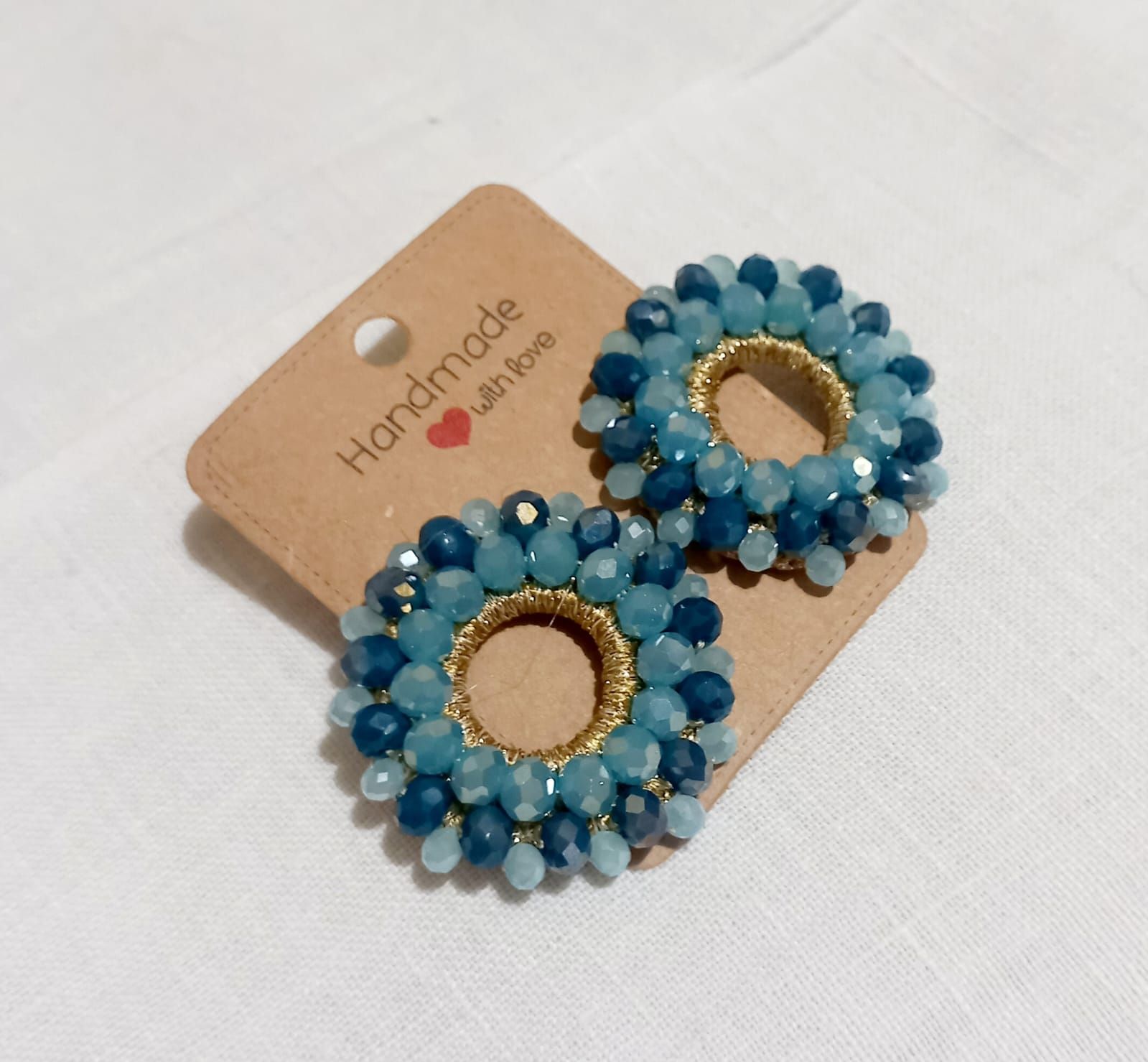 Orecchini con perline blu su cartoncino marrone per gioielli fatti a mano.