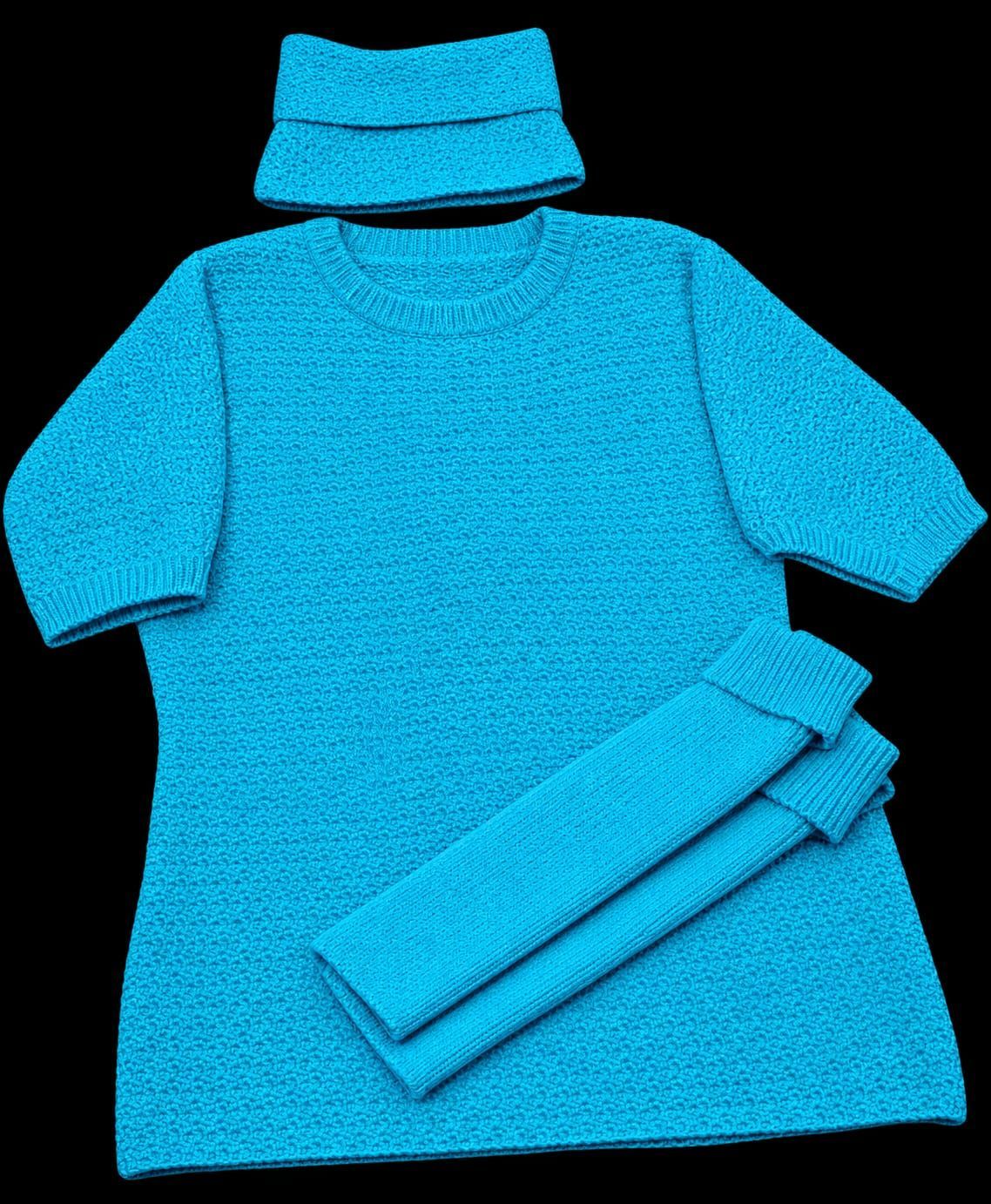 Abito blu in maglia con sciarpa abbinata e polsini arrotolati su sfondo nero.