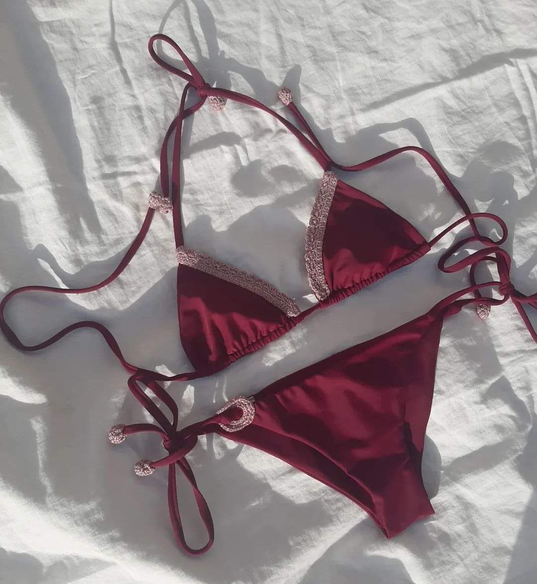 Bikini color bordeaux con bordi argentati su tessuto bianco, allacciato con laccetti sottili.