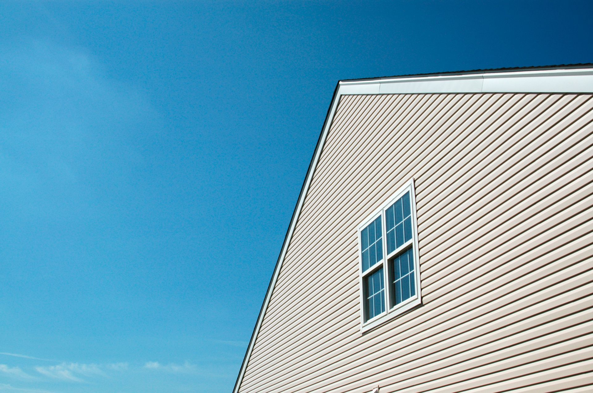 The side of a house with a window and a blue sky in the background.