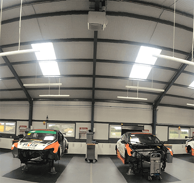 two cars are being worked on in a garage and one has a sticker on the hood that says tnt