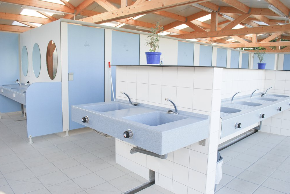 a bathroom with a lot of sinks and toilets in a campsite. Hot Water For Campsite'