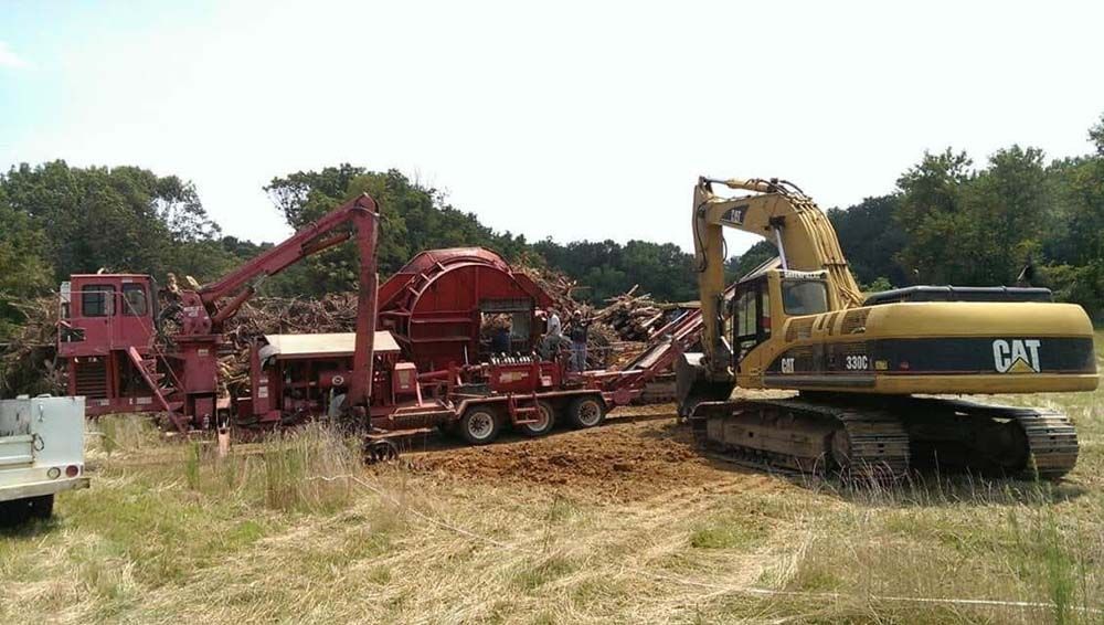 Yellow CAT excavator beside red farm machinery in a grassy field