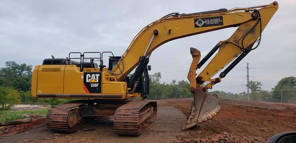 Yellow CAT excavator digging soil at a construction site with muddy tracks