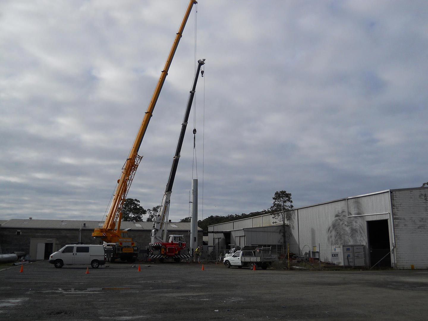 A White Van Is Parked In Front Of A Building With A Crane In The Background — North Coast Cranes In Bellingen, NSW