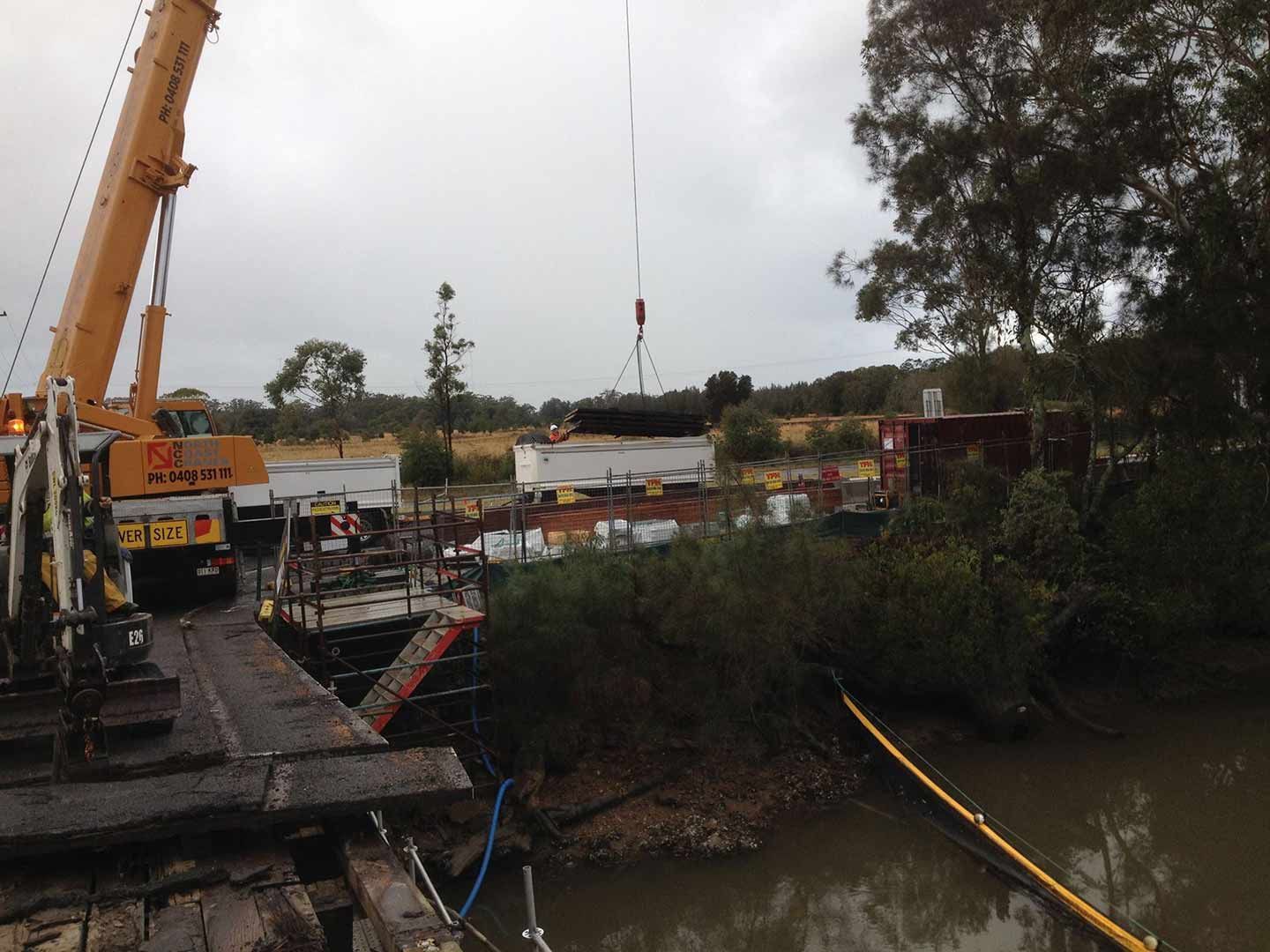 A Large Yellow Crane Is Lifting Something Over A Body Of Water — North Coast Cranes In Macksville, NSW