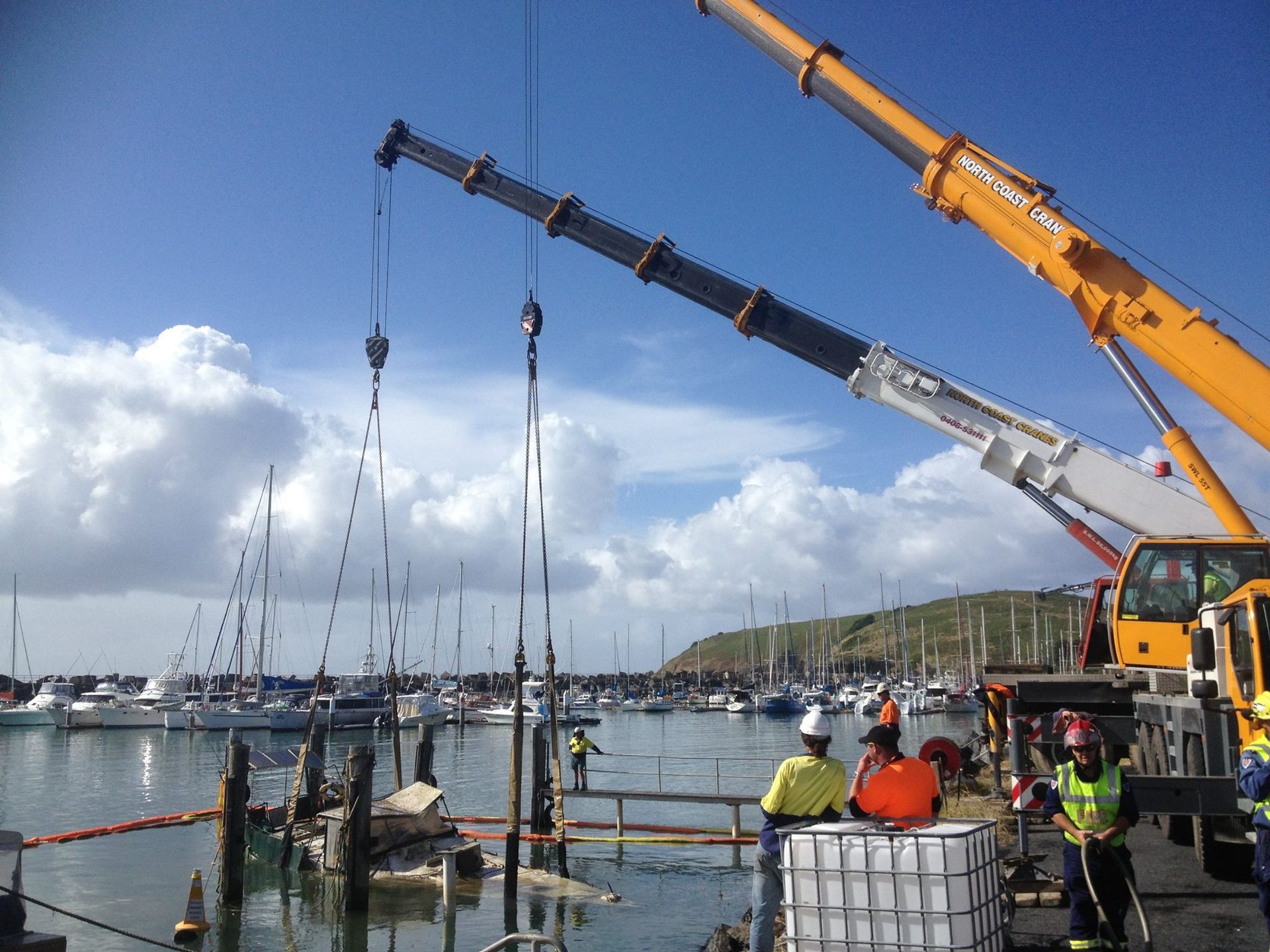 A Crane Is Lifting A Boat In A Harbor — North Coast Cranes In Bellingen, NSW