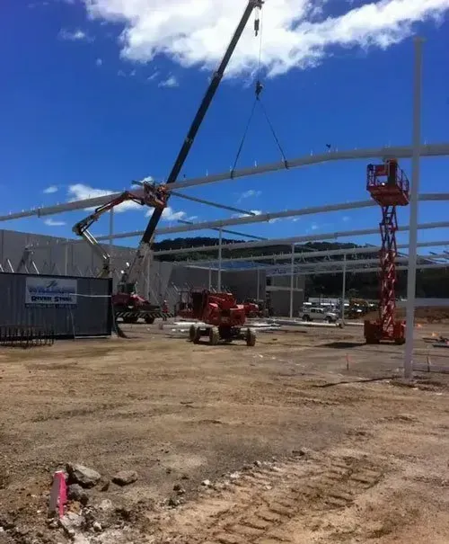 A Crane Is Lifting a Metal Structure in A Dirt Field — North Coast Cranes In Grafton, NSW
