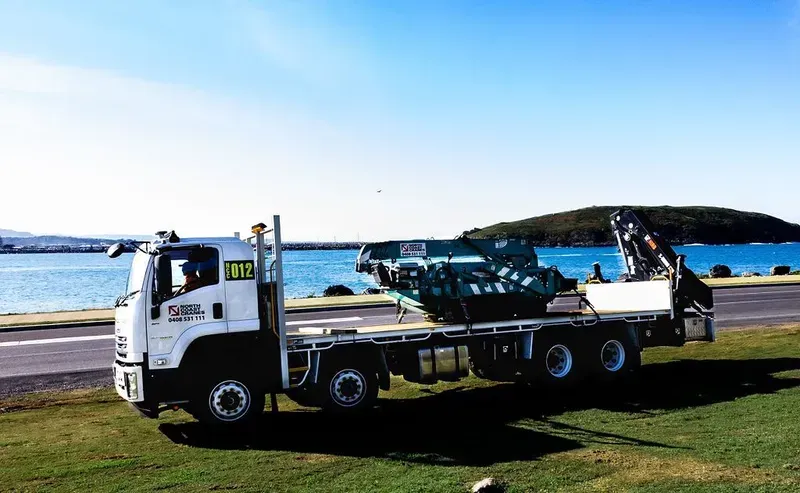 A White Truck with A Crane on The Back Is Parked in Front of A Lake — North Coast Cranes In Coffs Harbour, NSW
