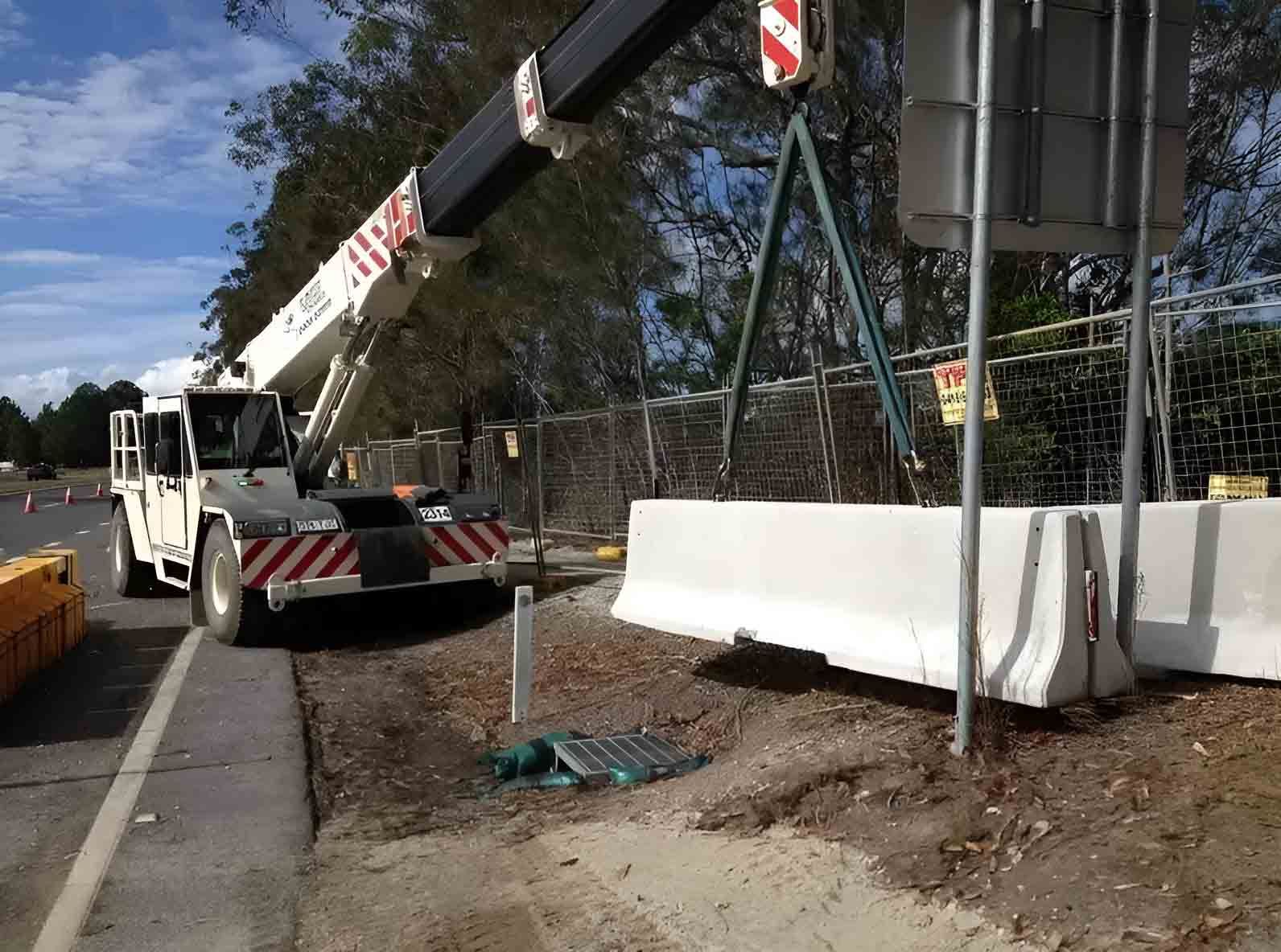 A Crane Is Lifting a Sign on The Side of The Road — North Coast Cranes In Woolgoolga, NSW