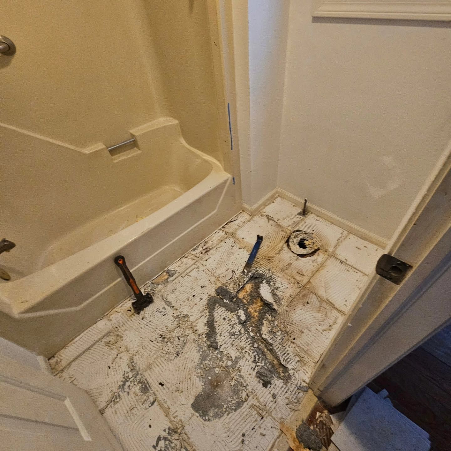 Bathroom floor with exposed plumbing and a tub/shower area during renovation