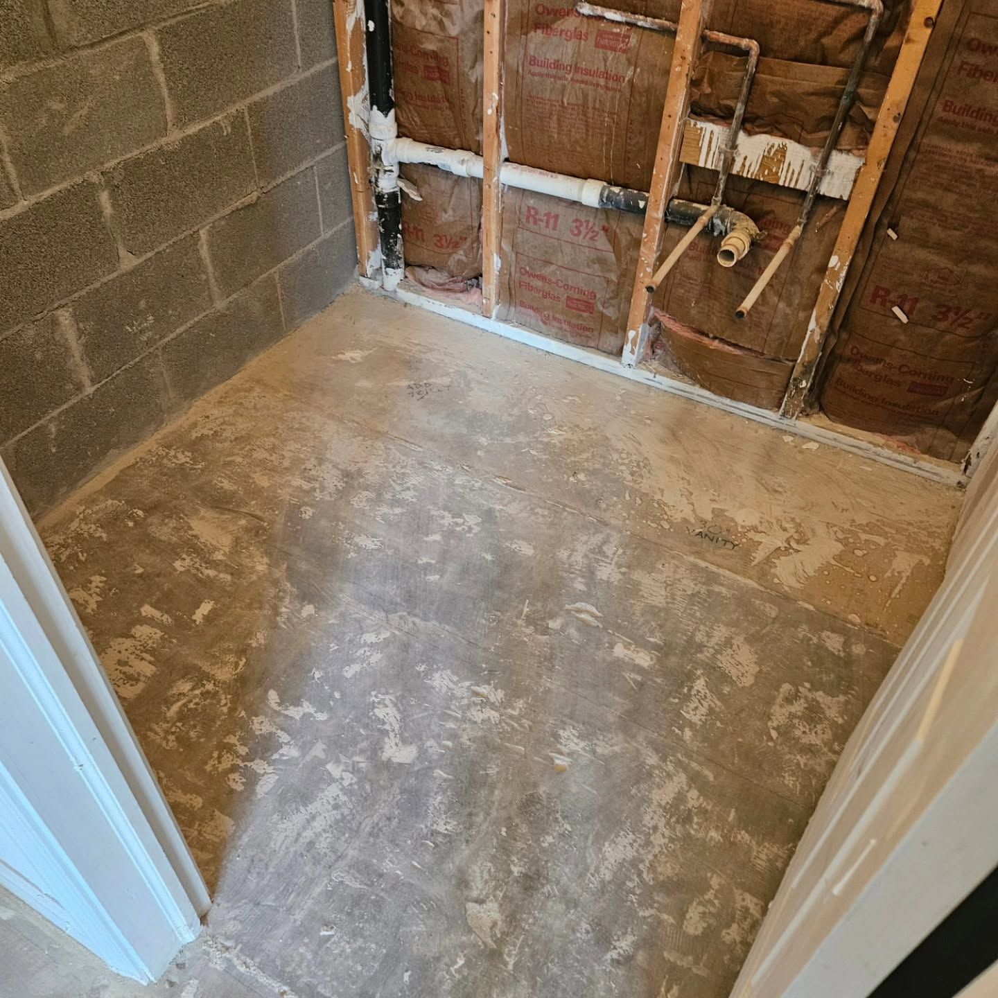 Empty room under renovation with exposed wall studs, cinderblock wall, and unfinished subfloor