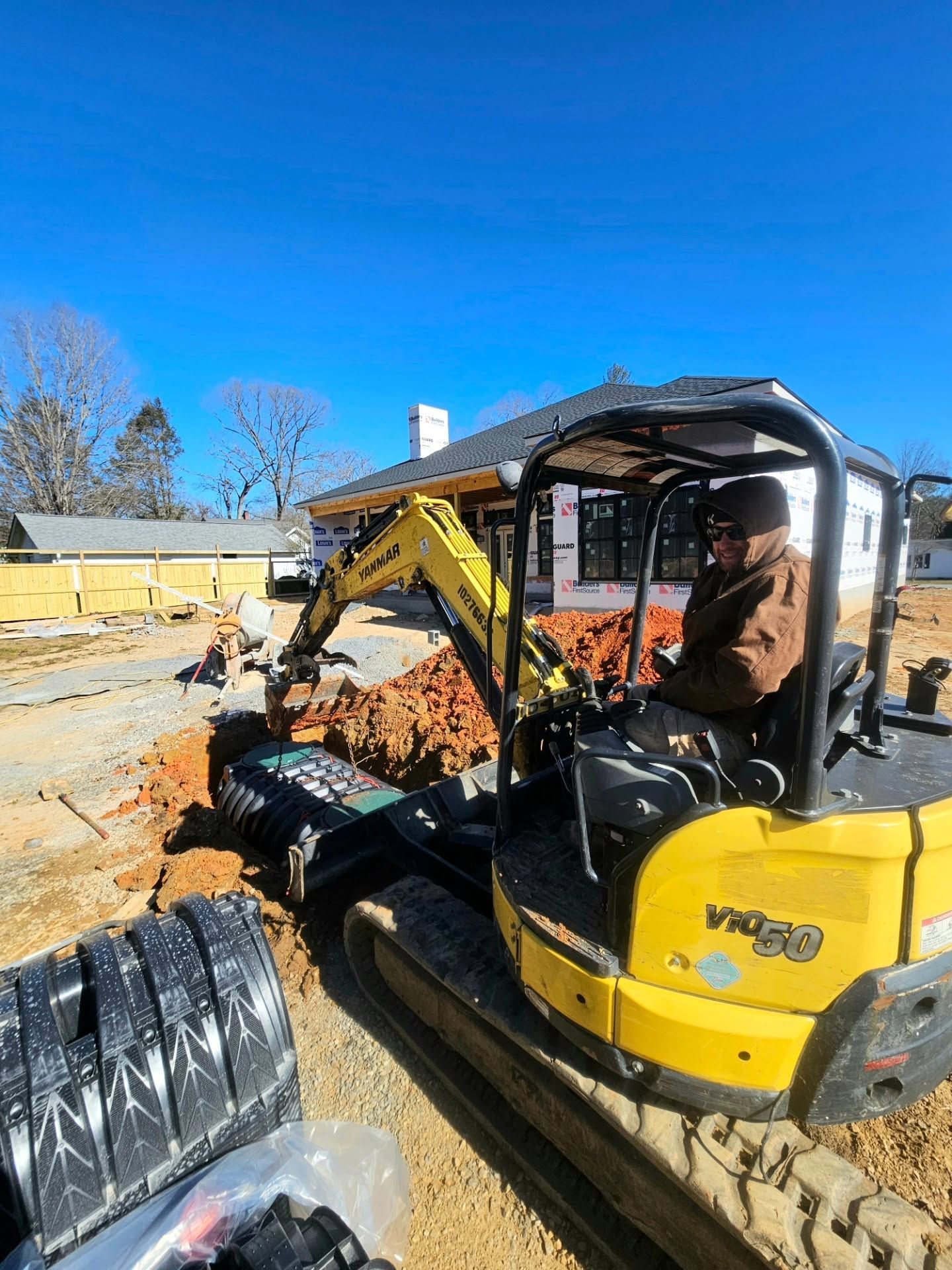 Yellow excavator moving dirt at a construction site under a clear blue sky