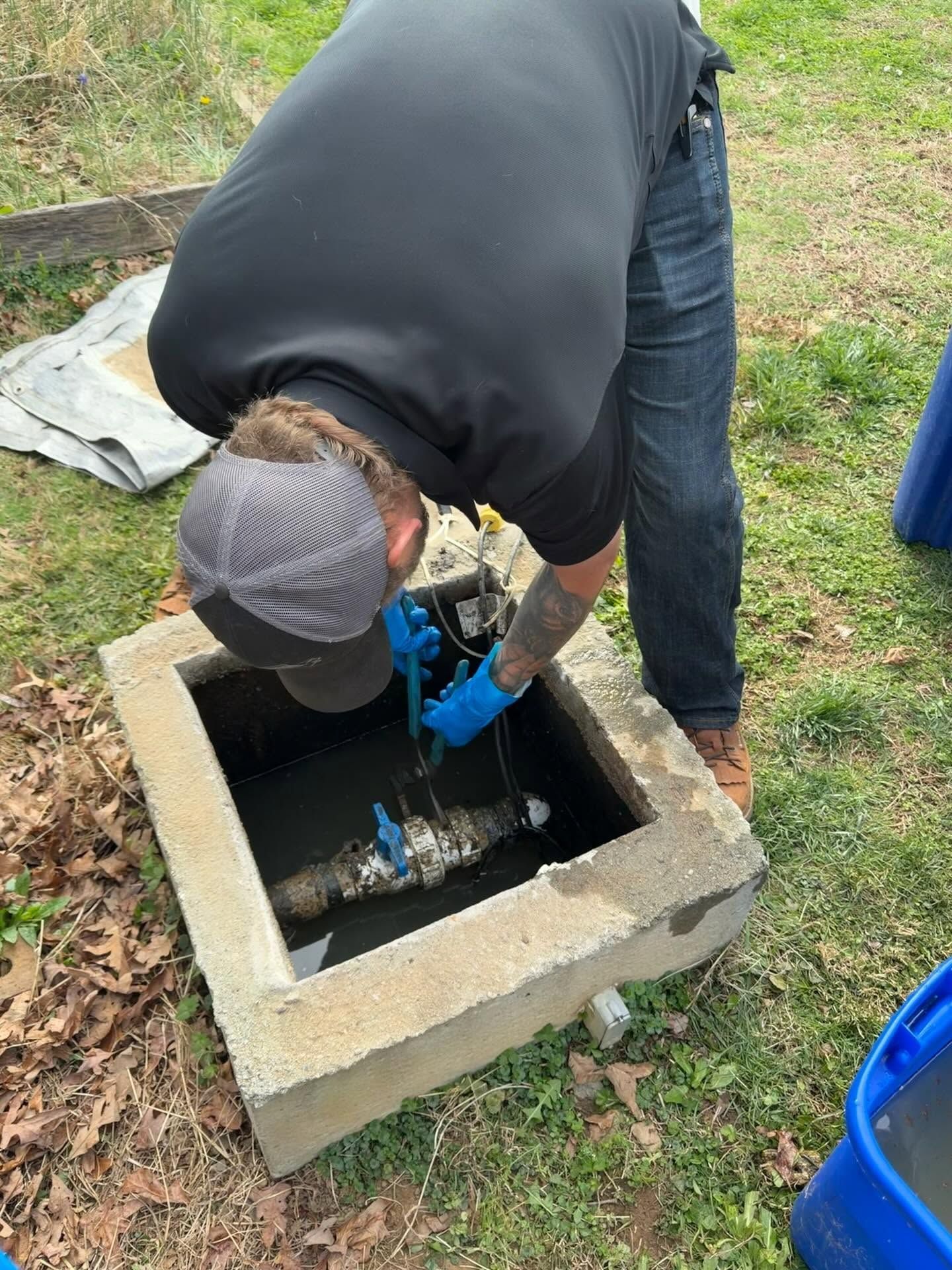 Worker in black shirt and blue gloves repairing a utility box outdoors.