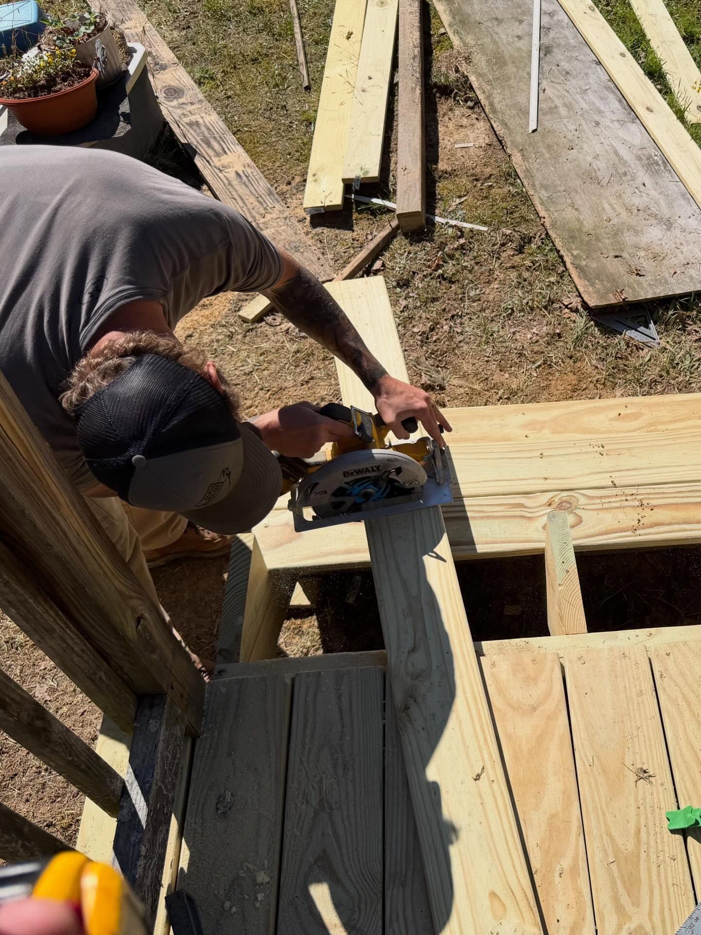 Person using a circular saw to cut wood on an outdoor deck under construction