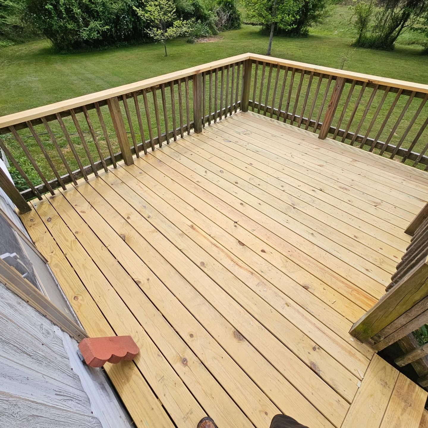 Wooden backyard deck with railings, viewed from a doorway, overlooking a grassy yard