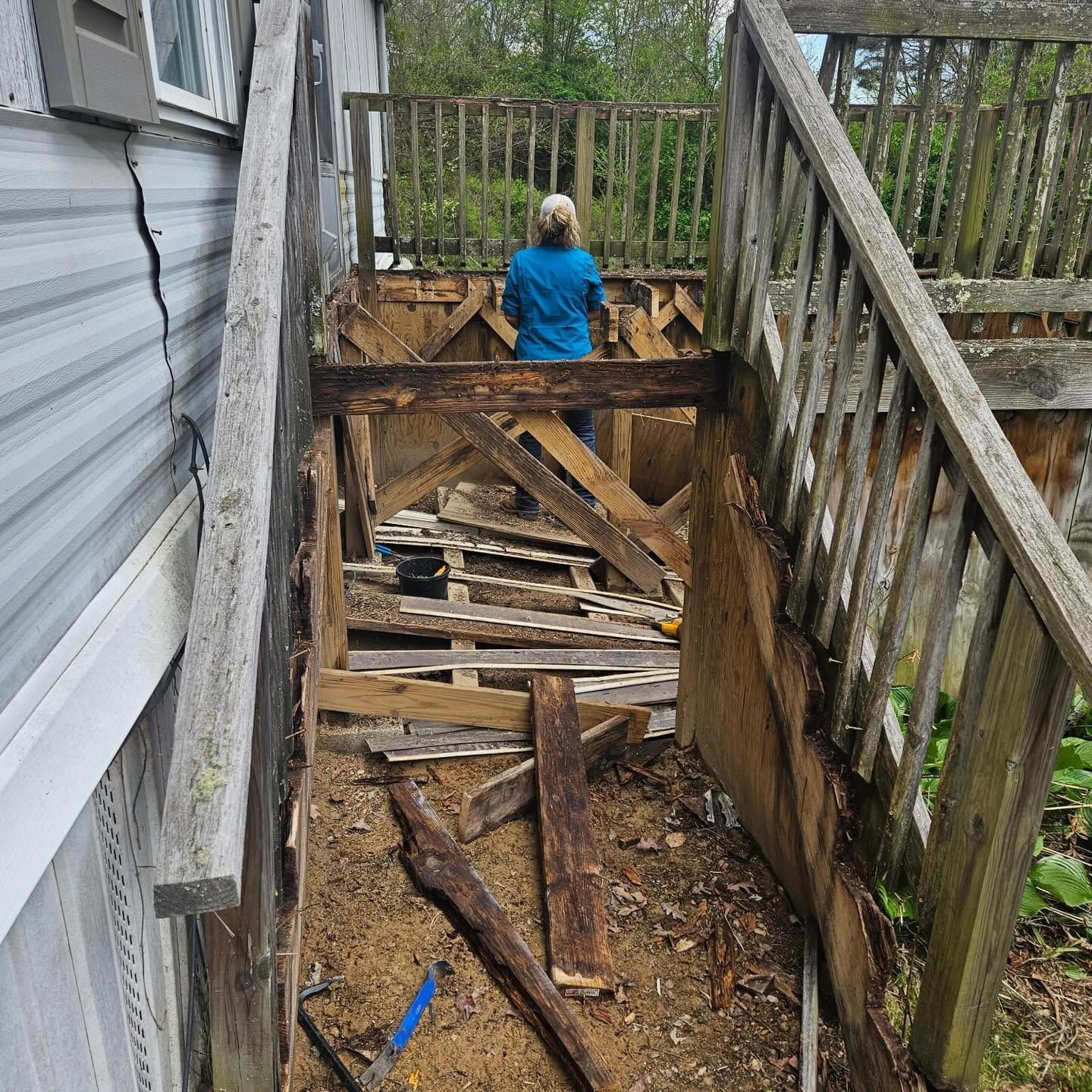 Damaged wooden stairway with debris, viewed from above, with a person in a blue shirt at the bottom