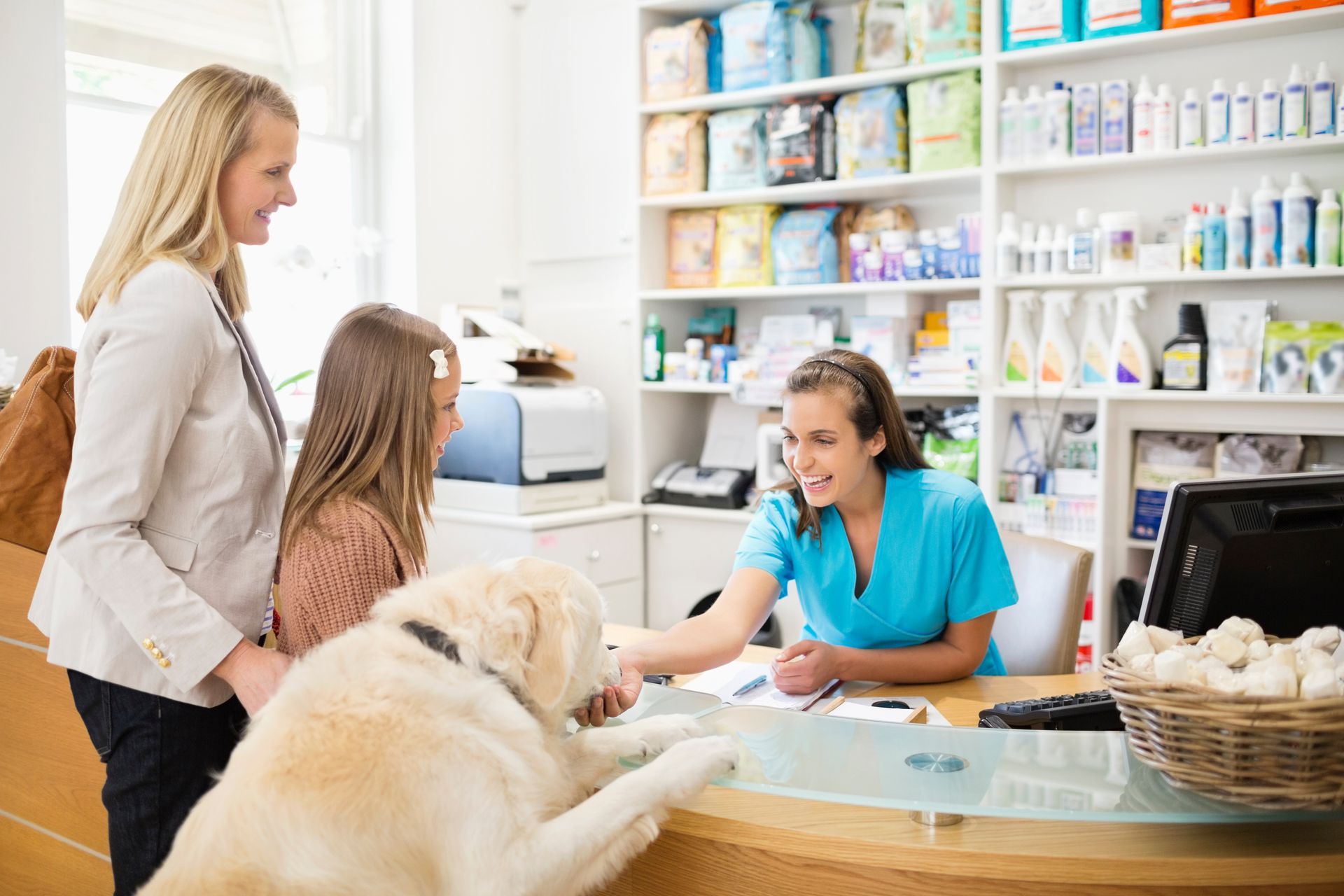 Friendly veterinarian clinic staff assisting pet owner with dog at front desk check-in.
