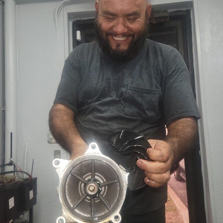Man holding parts of an impeller, smiling. Gray shirt, indoors | Auto & Truck Solutions