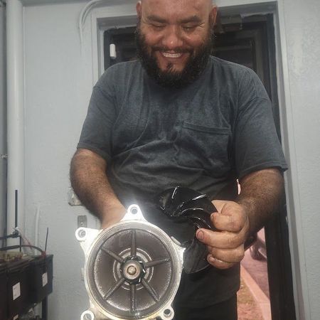 Man holding parts of an impeller, smiling. Gray shirt, indoors | Auto & Truck Solutions