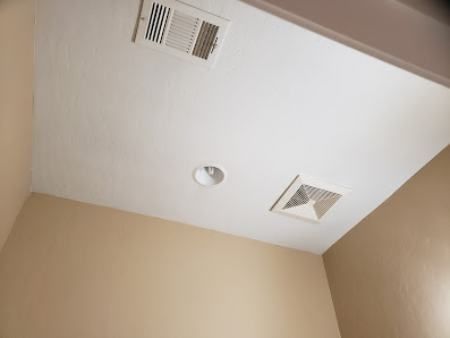 White ceiling with two vents, a light fixture, and beige walls.