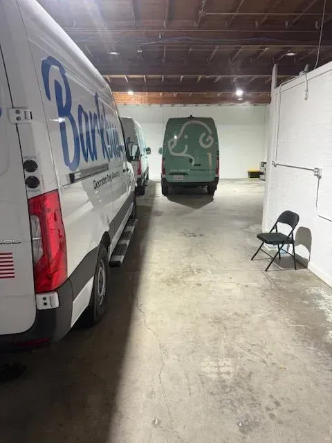 Indoor warehouse with parked vans, one folding chair, and a concrete floor.