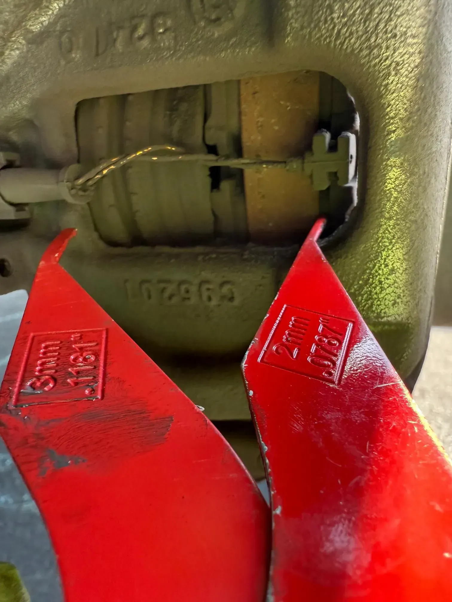 Close-up of a mechanical component with red safety guards and a cable inside a metal housing.