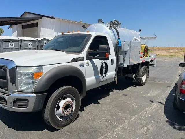 White utility truck parked on a road beside a building under a clear blue sky