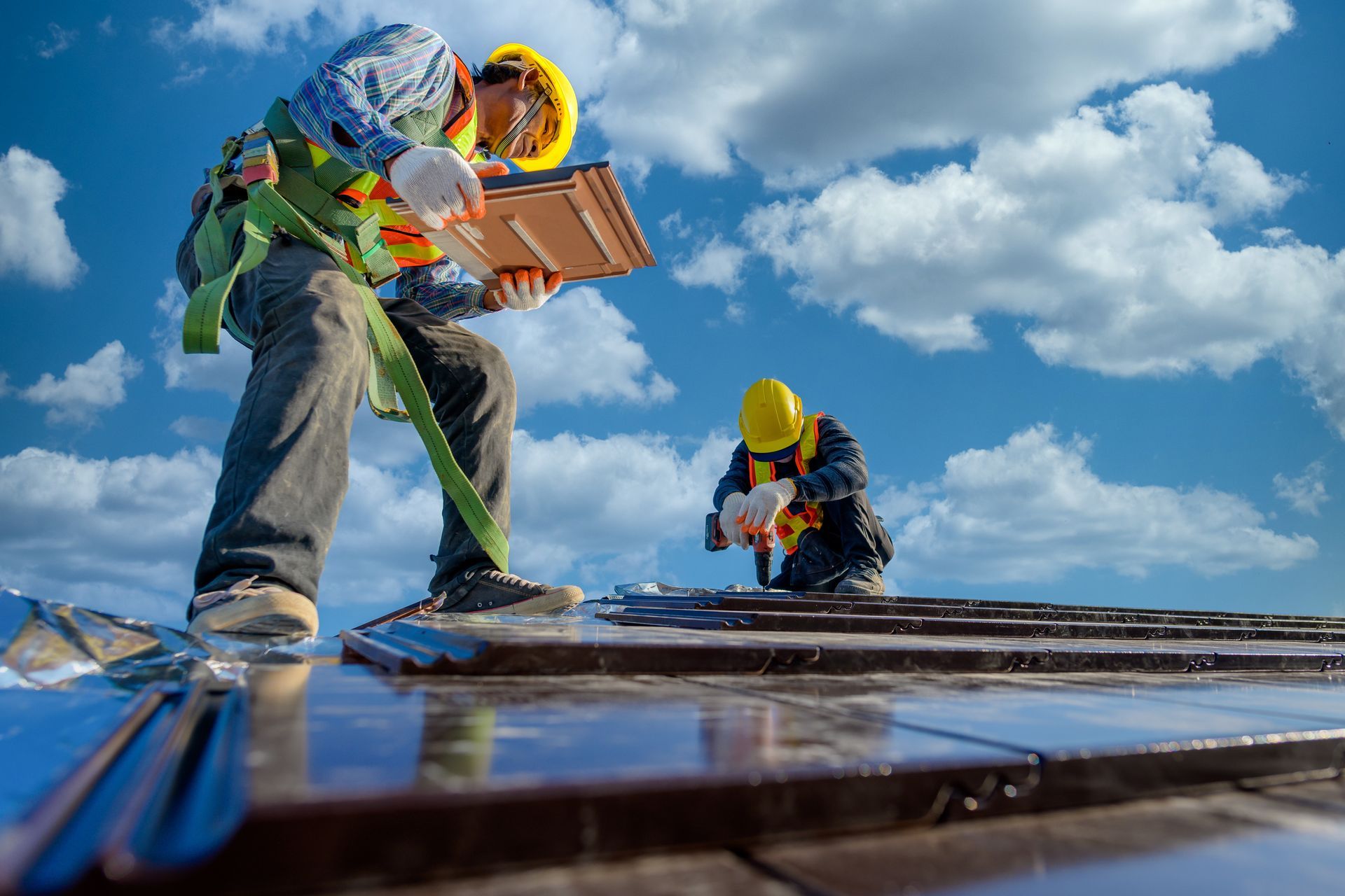 Two male workers wearing safety clothes Installing the roof tile house.