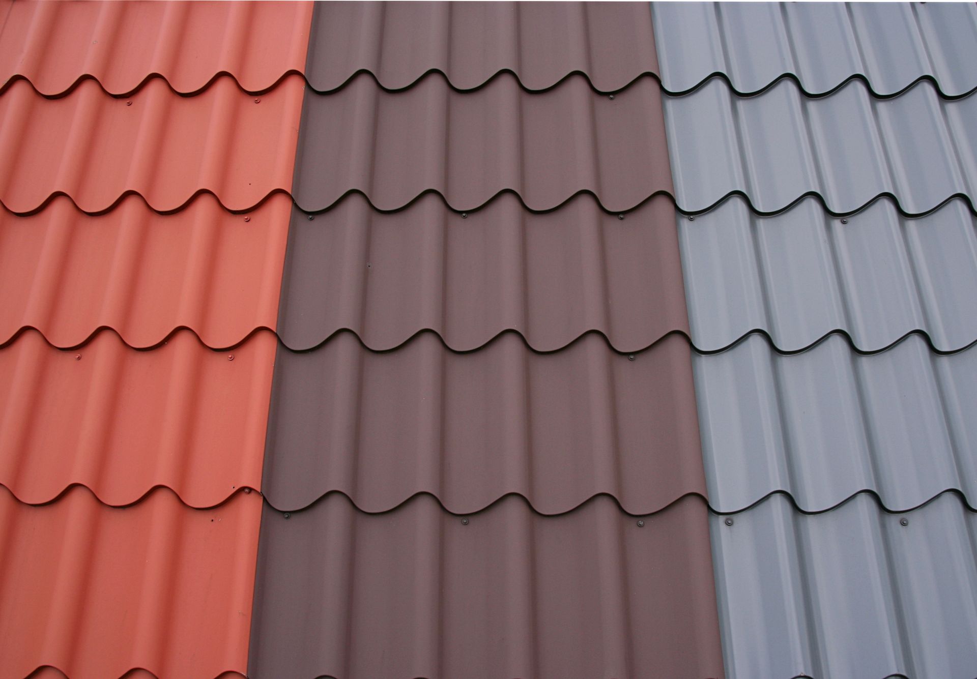 Three metal roof panels: red, brown, and gray, with a wavy, tile-like design.