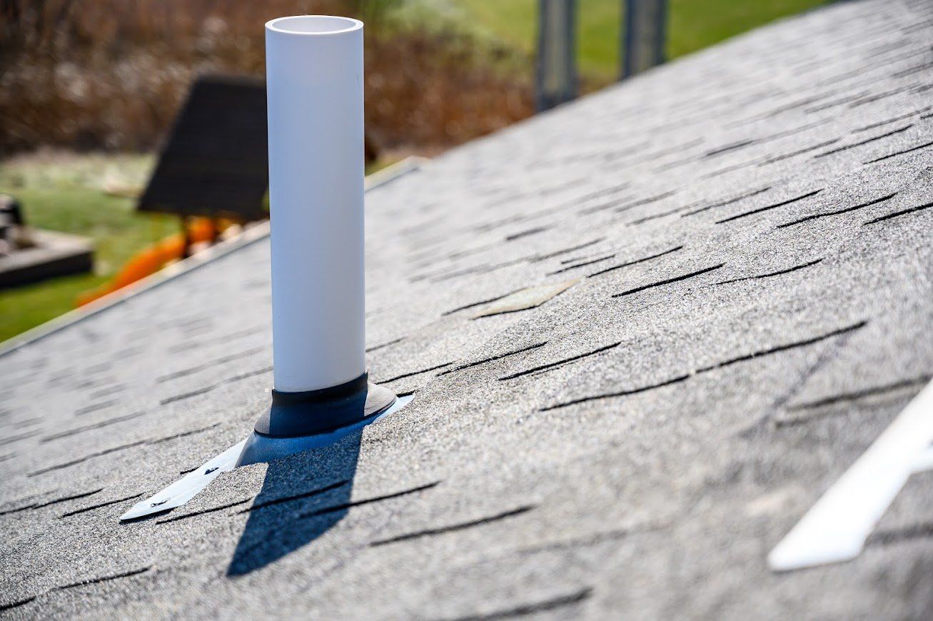 Gray shingle roof with a white vent pipe extending upwards.