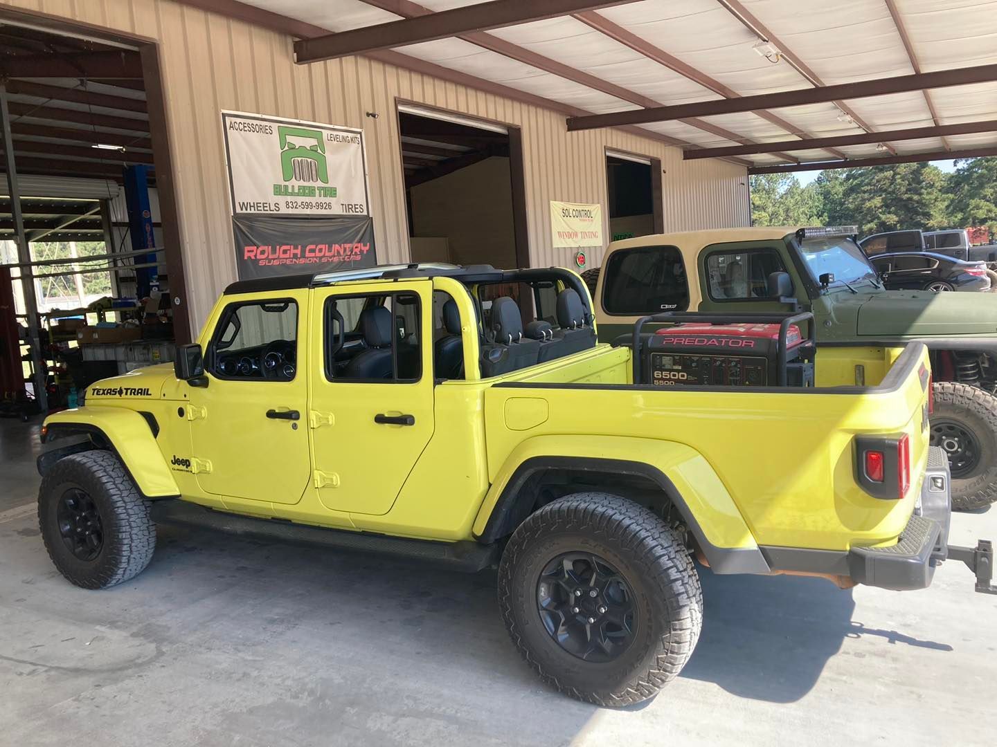 Bright yellow off-road pickup truck parked under a metal-roofed shed