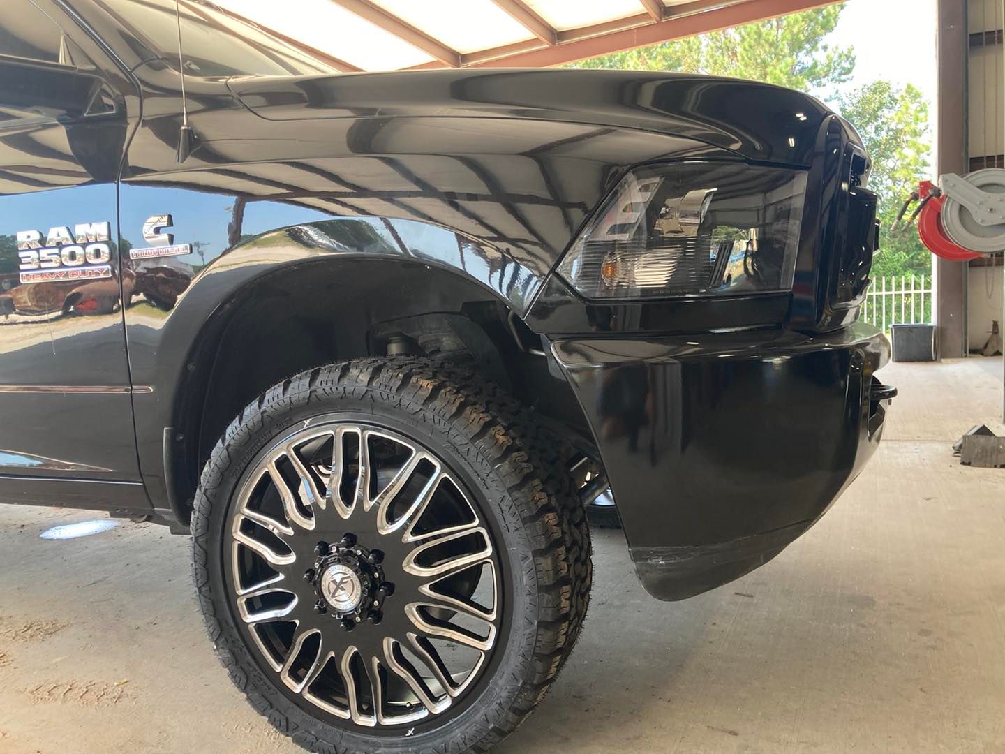 Black lifted truck front quarter with custom alloy wheel parked indoors
