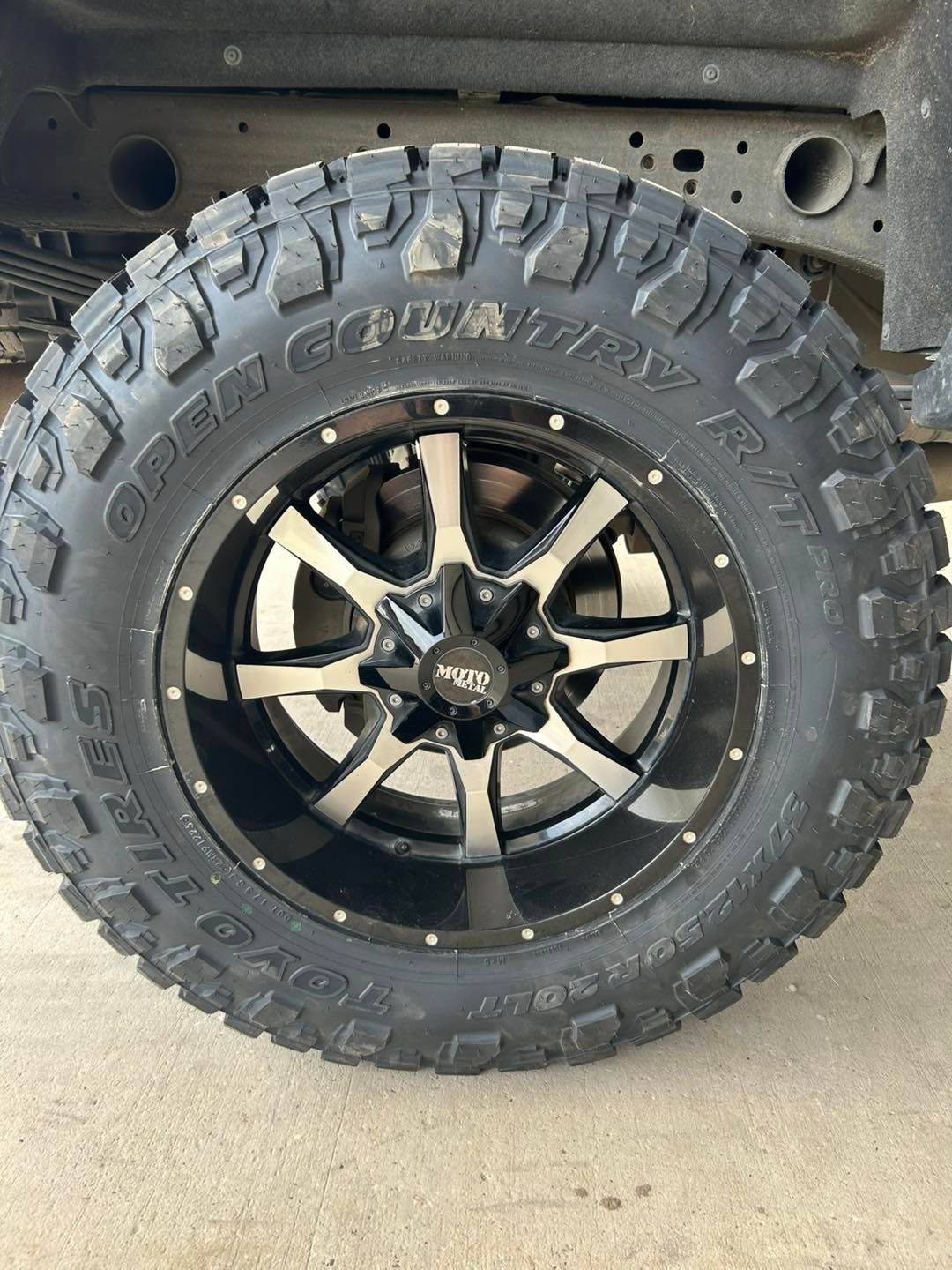 Close-up of a black off-road tire and wheel mounted on a vehicle.