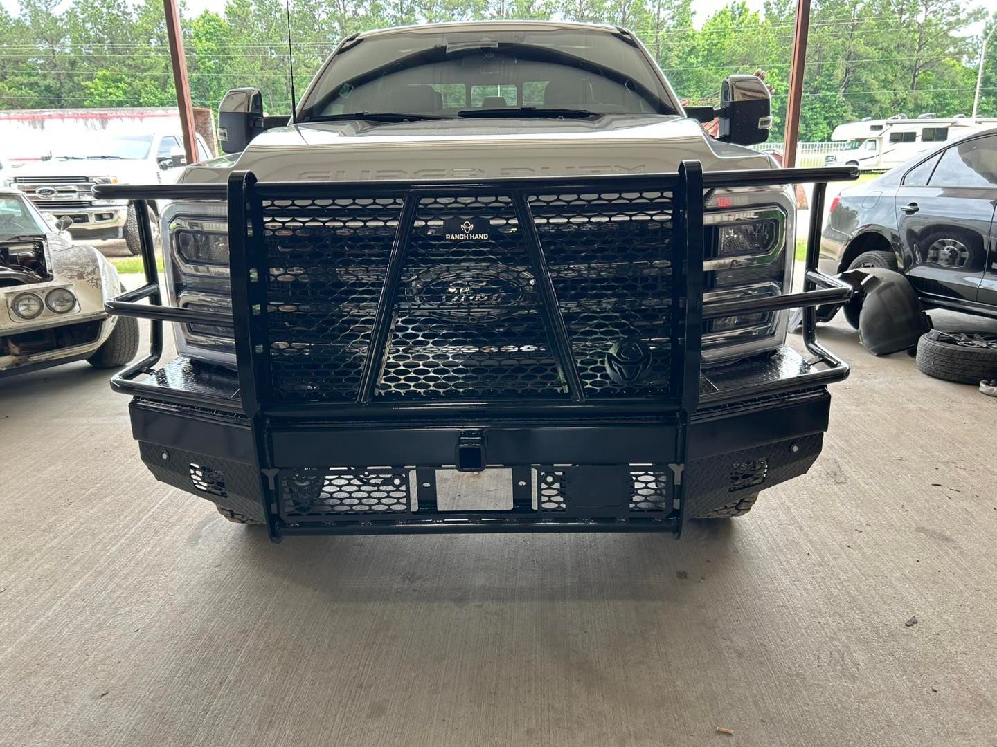 Front view of a black pickup truck with a heavy-duty grille guard parked under a covered area.
