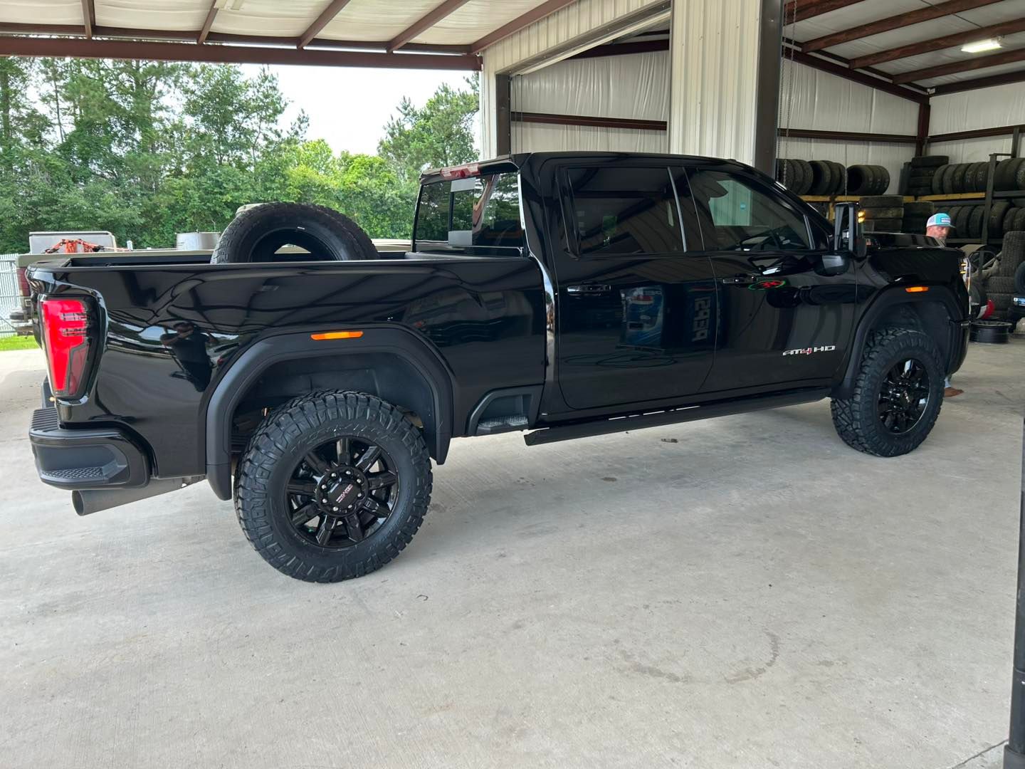Black pickup truck parked under a metal carport, side view