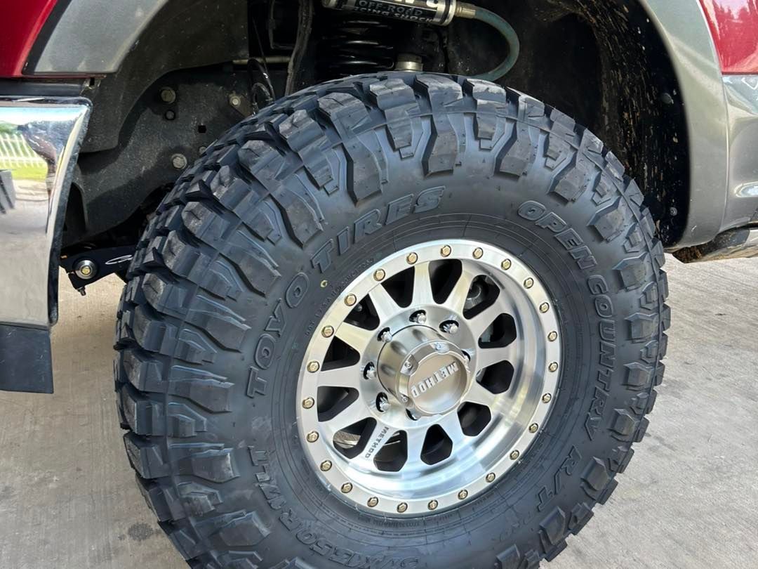 Close-up of an off-road truck tire and silver rim under a lifted vehicle