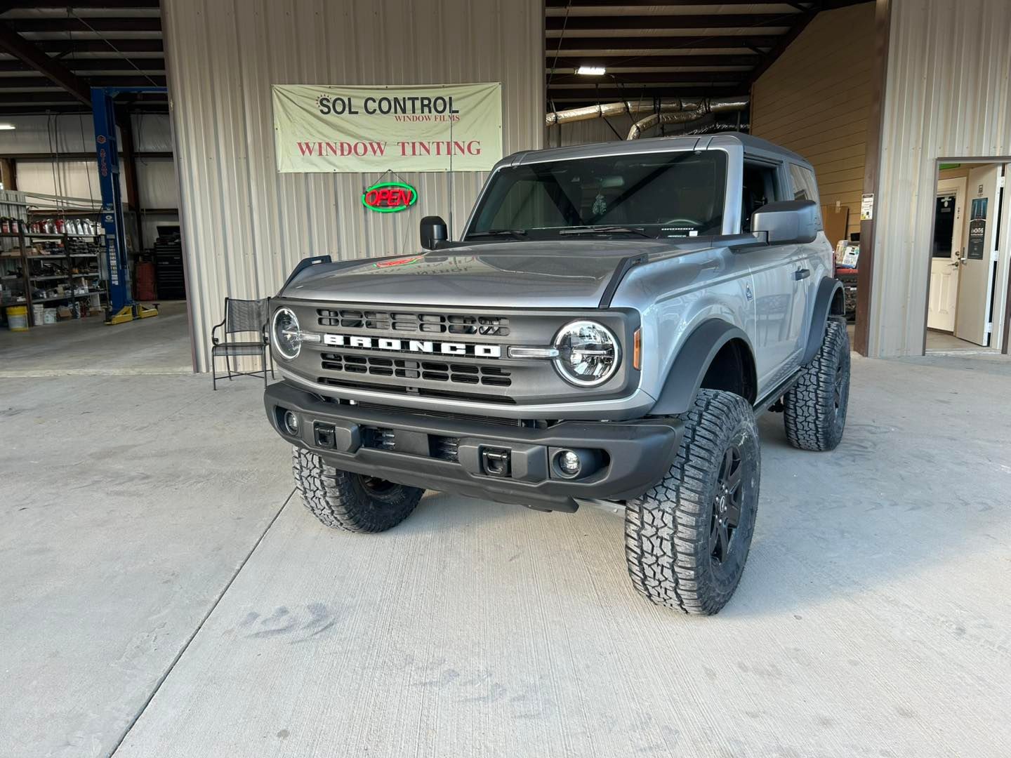 Gray Ford Bronco parked in a garage with a “No Soliciting” sign in the background