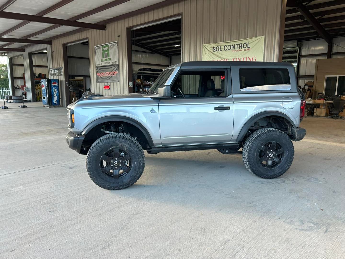 Light blue lifted off-road SUV parked outside a service garage