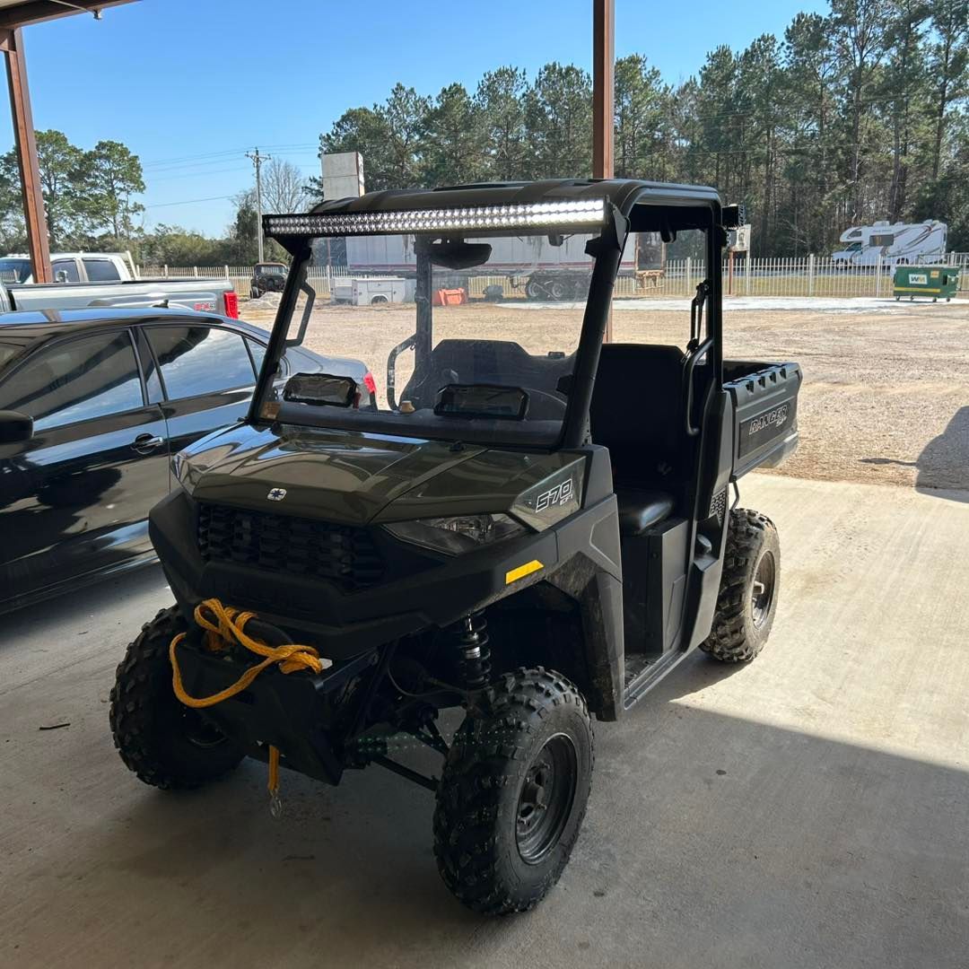 Black off-road utility vehicle with a windshield parked under a covered area.