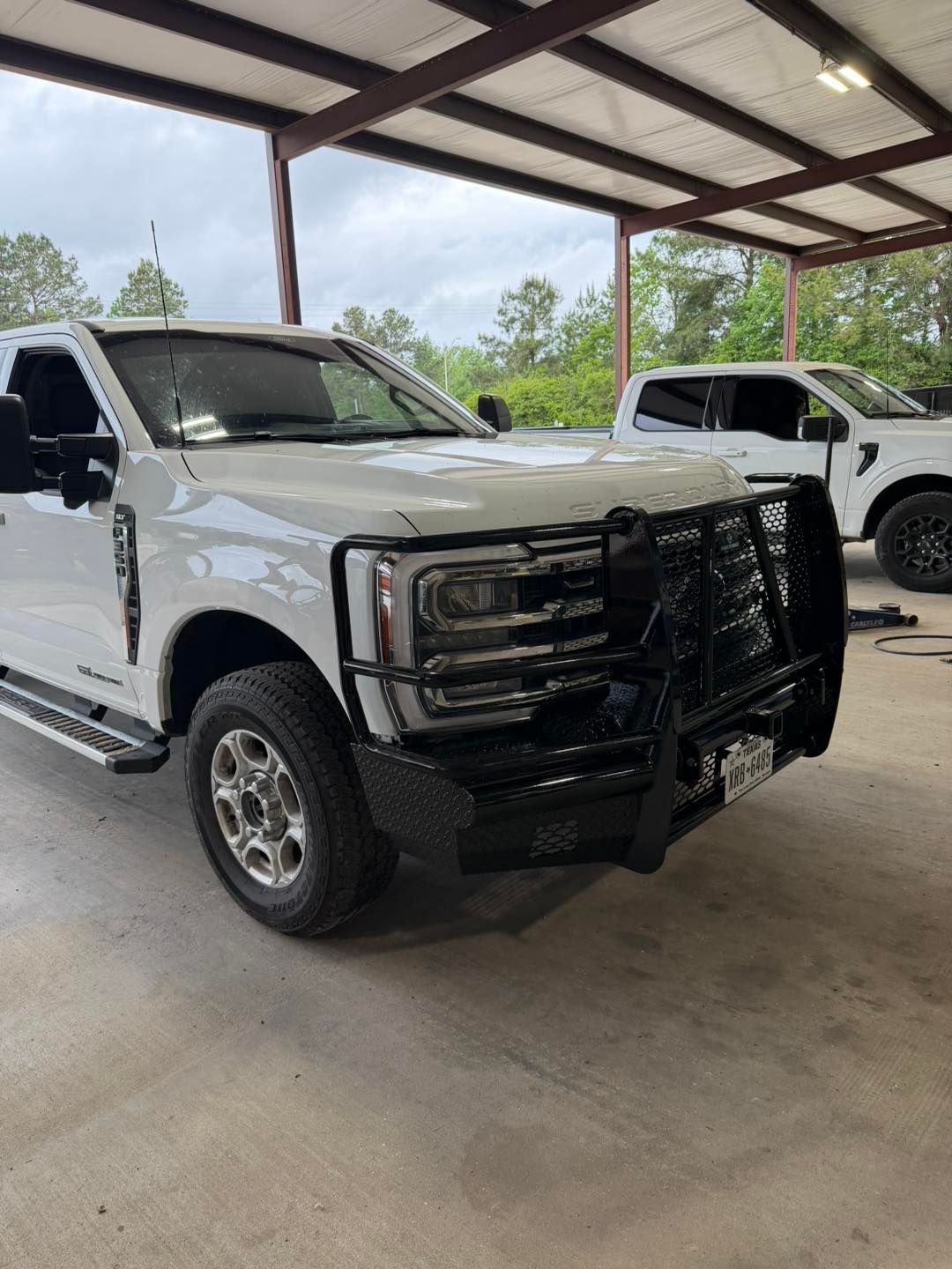 White pickup truck with a black grille guard parked under a covered structure