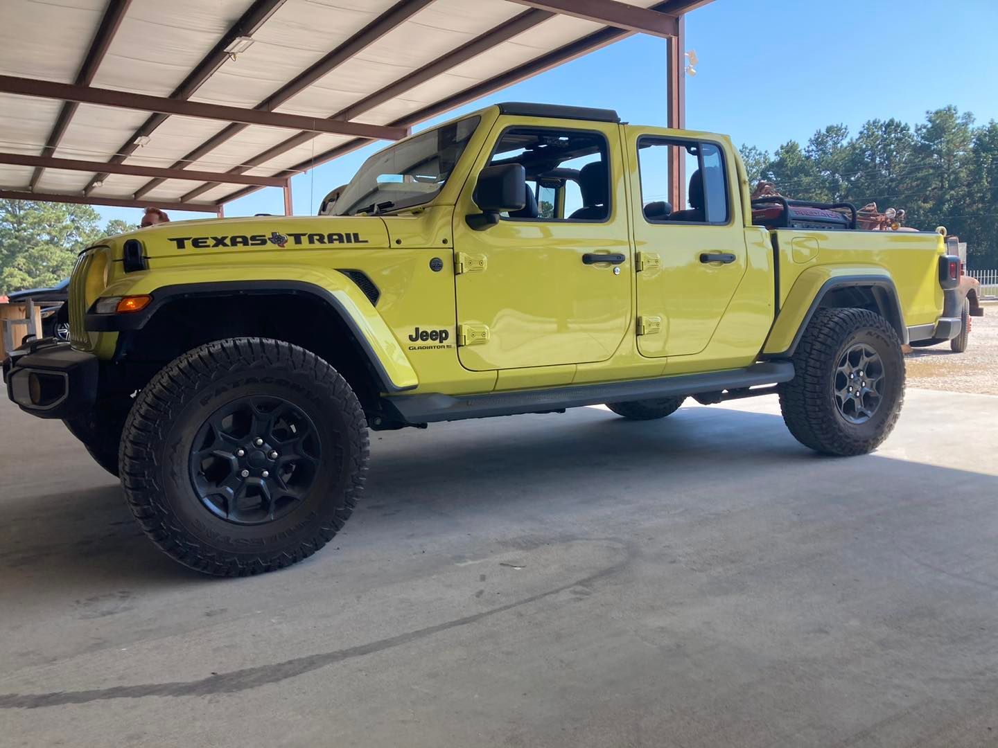 Yellow Hummer pickup truck parked under a carport