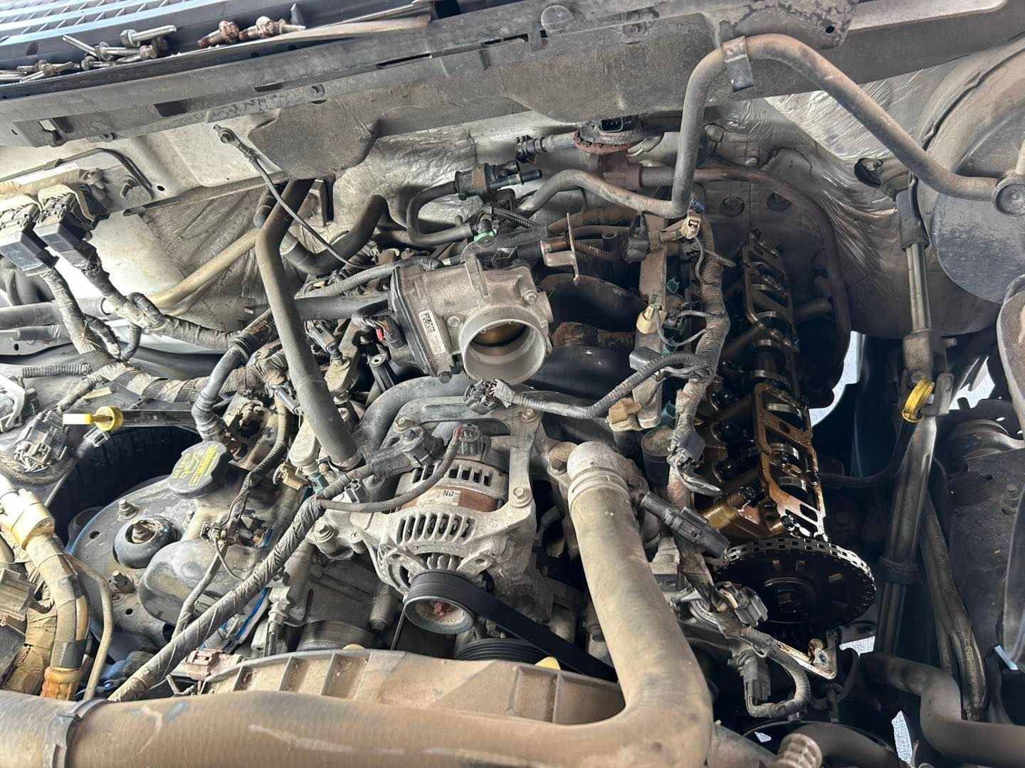 Damaged car engine bay with exposed, tangled components and hoses under the hood