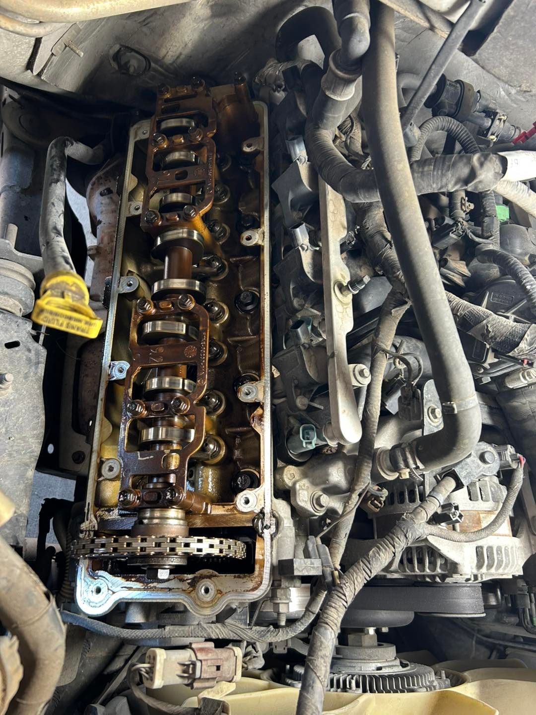 Close-up of an engine with the valve cover removed, exposing camshafts and engine components.