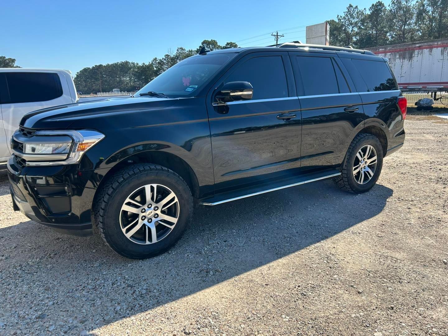 Black SUV parked on a gravel lot under a clear blue sky.